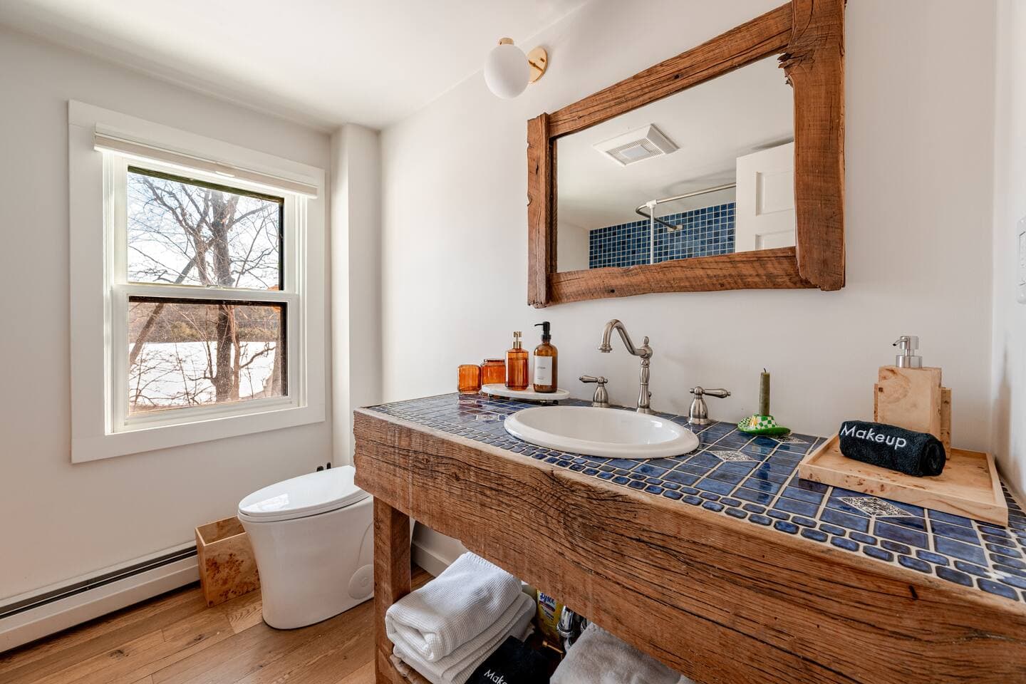Bathroom with rustic wood vanity and hand-laid blue mosaic tile at The Cedar Stock Cabin