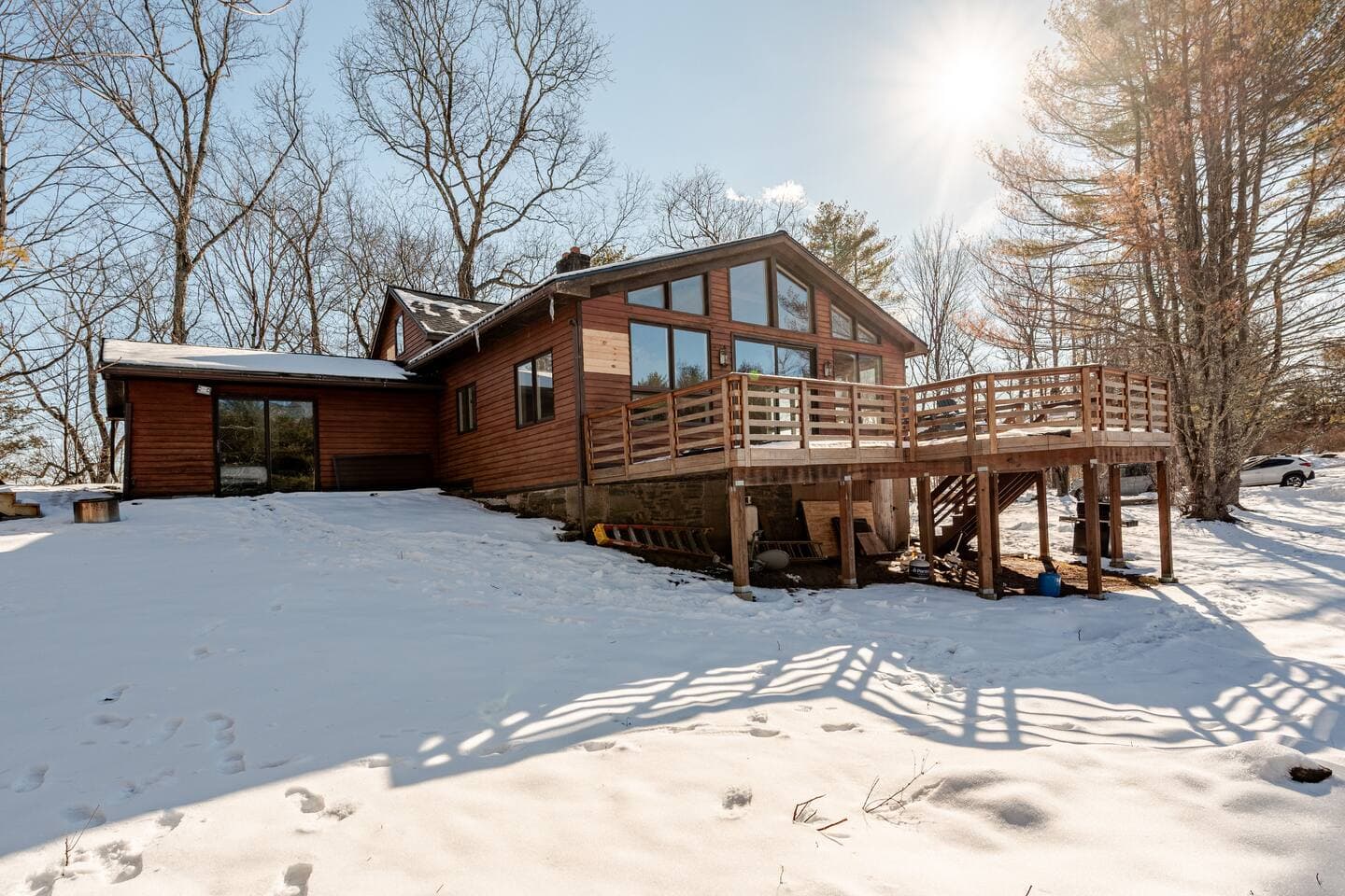Wide-angle view of The Cedar Stock Cabin with wrap-around deck surrounded by snow